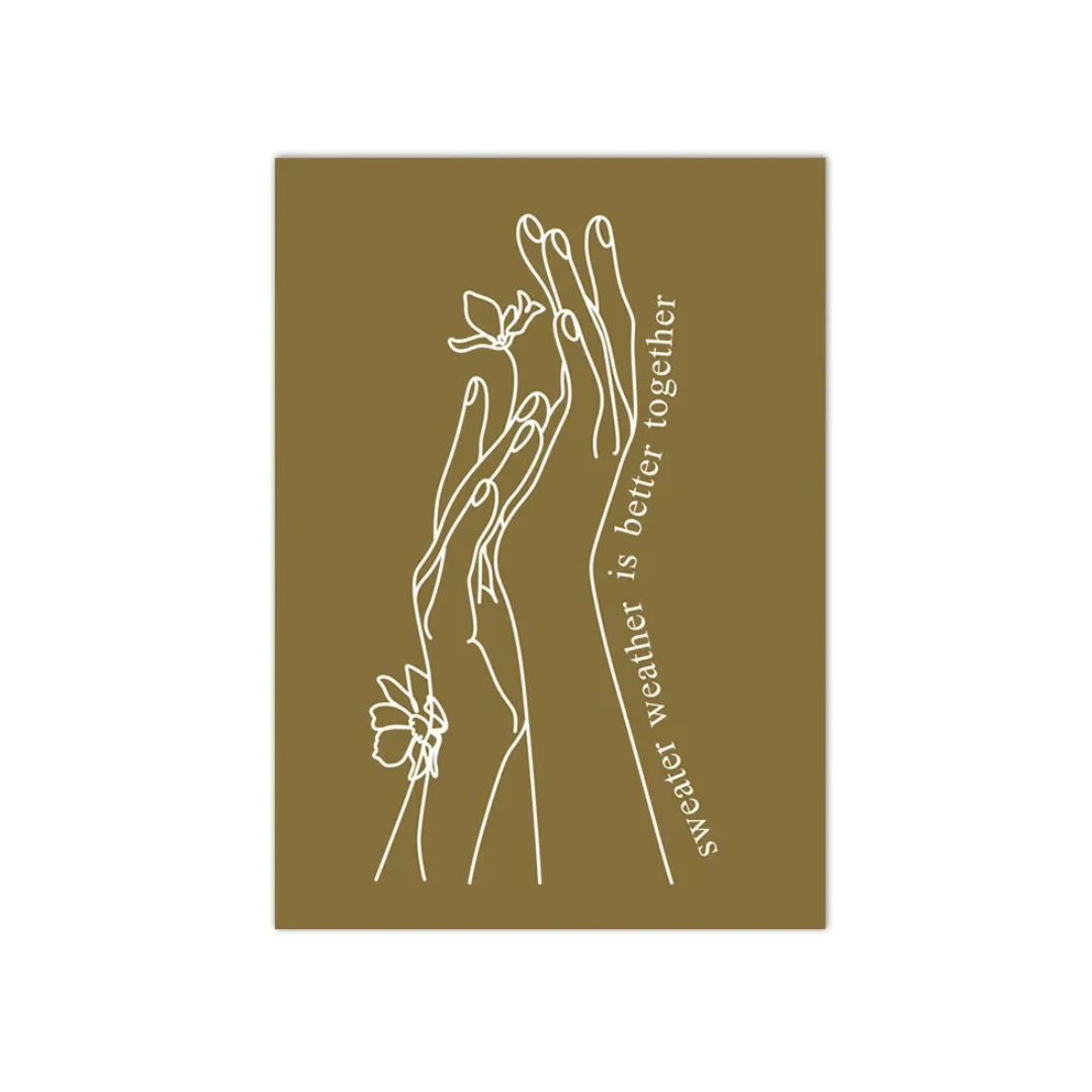 A rectangular art print with a solid olive-brown background, featuring a minimalist white line drawing of intertwined hands holding flowers, with the quote 'sweater weather is better together' printed vertically in white.