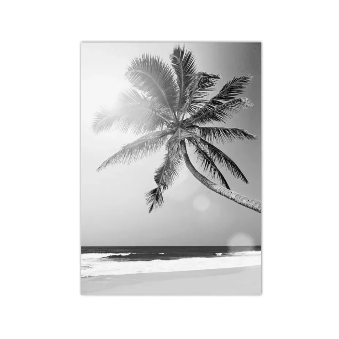 A black and white photographic art print of a leaning palm tree on a beach, displayed as a vertical canvas mockup against a white background.