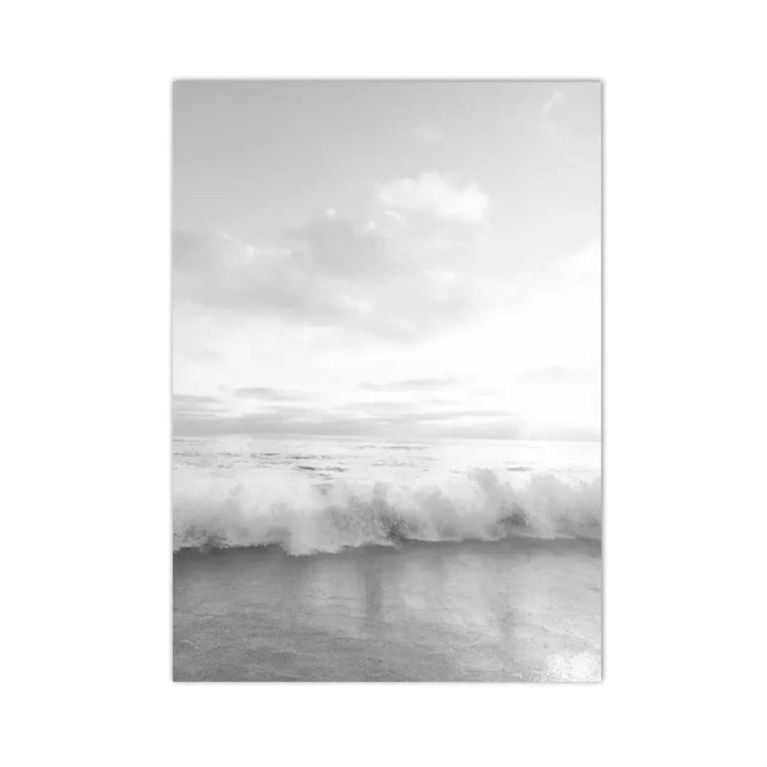 A vertical black and white photographic print of a wave breaking on a beach under a cloudy sky, shown as a rectangular canvas or poster centered on a white background.