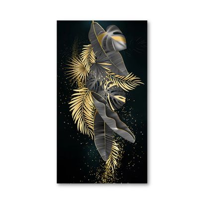 A vertical rectangular wall art print featuring stylized tropical leaves in metallic gold and dark gray on a black background, shown against a plain white wall.