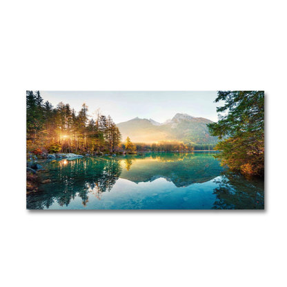 A panoramic landscape canvas print depicting a serene mountain lake at sunrise, with golden sunlight filtering through pine trees and reflecting perfectly on the calm water, shown against a plain white background.