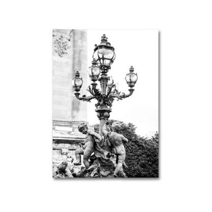 A black and white photographic print of an ornate classical street lamp with cherub statues, displayed as a vertical canvas against a white background.