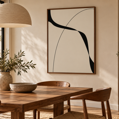 A framed abstract wall art print with black curved lines on a warm cream background, hanging above a wooden dining table in a softly lit dining room.