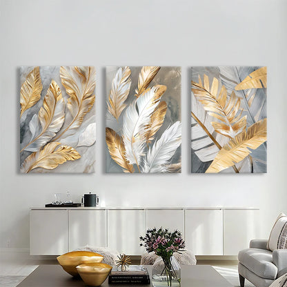Three abstract wall art pieces with gold and silver leaves on a white wall.