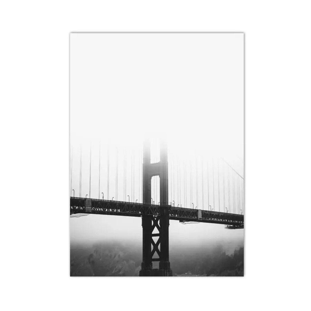 A vertical black and white photographic print of a suspension bridge tower emerging from dense fog, shown as a rectangular canvas against a white background.